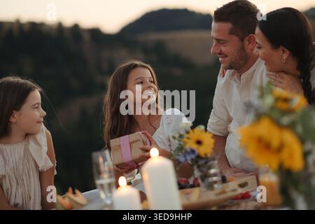 Glückliche Familie mit Kindern, die in der Natur den Mädchengeburtstag feiern. Stockfoto