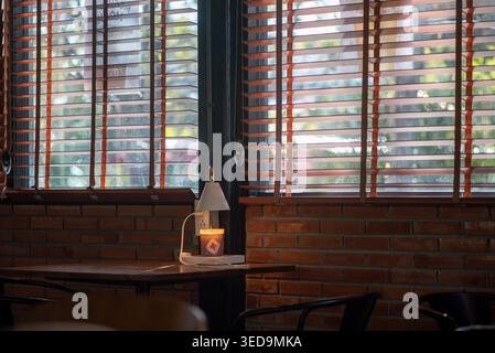 Ein ruhiges Café-Interieur mit warmer Beleuchtung, gemütlichem Ambiente und stilvoller Einrichtung. Genießen Sie die ruhige Atmosphäre, die durch sanfte Schatten und natürliche Natur erzeugt wird Stockfoto