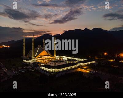 Aus der Vogelperspektive von Faisal Masjid, beleuchtet in der Abenddämmerung, mit den Margalla Hills im Hintergrund unter einem bewölkten Sonnenuntergang Islamabad, Islamabad Capital Ter, Stockfoto