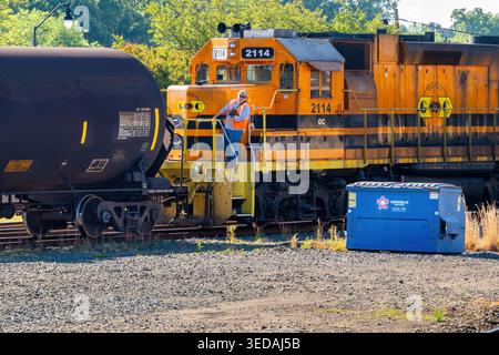 Sanford, North Carolina, USA – Mai 2026: Ein Eisenbahnarbeiter koppelt Güterwagen mit einer Lokomotive auf einem Bahnhofsgelände in Sanford. Stockfoto
