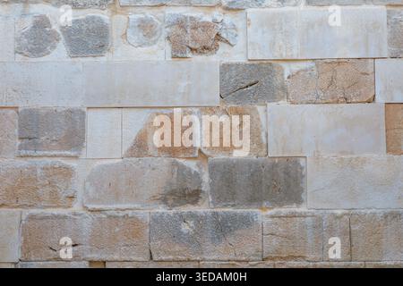 Alte Steinmauer mit verwitterten Kalksteinblöcken und rustikaler Textur Stockfoto