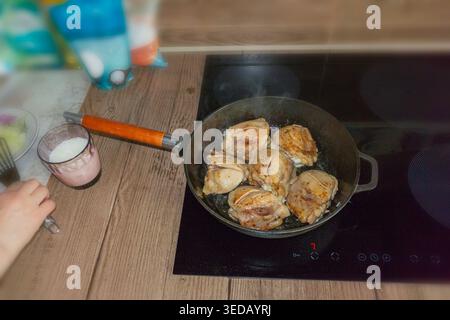 Ich brate Hähnchenschenkel in einer Pfanne. Geselliges Essen, traditionelle Hausmannskost, slawische Küche Stockfoto