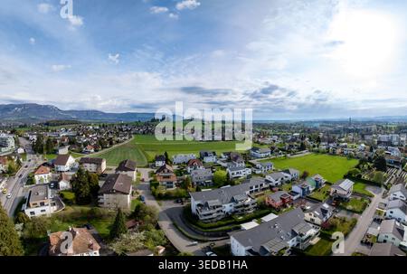 Luftaufnahme von Wohnhäusern, grünen Wiesen und fernen Bergen unter hellem Himmel in Biberist, Solothurn, Schweiz. Stockfoto