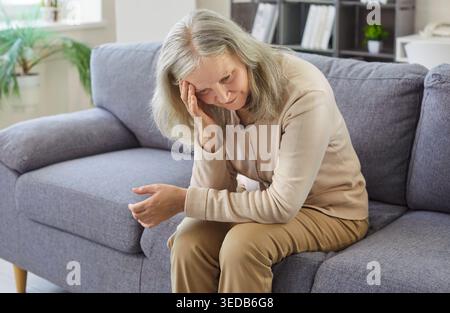Traurige Ältere Frau Mit Kopfschmerzen Auf Dem Sofa Zu Hause Stockfoto