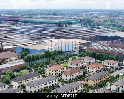 Blick aus der Vogelperspektive auf den großen Industriekomplex und die Wohnhäuser umgeben von grünen Bäumen und der flachen Landschaft Dalmine, Lombardei, Italien. Stockfoto