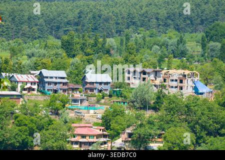 Aus der Vogelperspektive von Wohnhäusern eingebettet in üppige Waldlandschaften in Pahalgam, Kaschmir, Indien, ideal für Reise- und Tourismusmarketing. Stockfoto