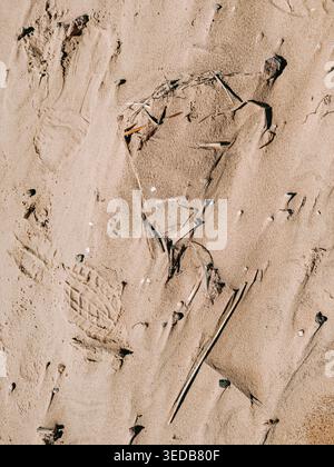 Minimalistische Strandszene mit einer Herzform aus weichem Sand mit sichtbaren Fußabdrücken und natürlichen Trümmern. Ideal für Themen wie Liebe, Reisen, Romantik Stockfoto