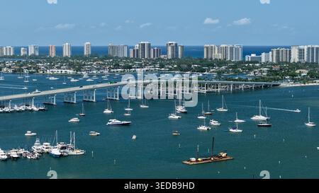 Blick aus der Vogelperspektive auf Peanut Island und die Blue Heron Bridge mit zahlreichen Booten, die im türkisfarbenen Wasser ankern, und die Skyline der Küste Palm Beach County, Stockfoto