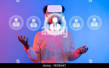 Ein junger Erwachsener, der ein Virtual-Reality-Headset trägt, interagiert mit digitalen Netzwerkelementen und symbolisiert moderne Kommunikation und soziale Interaktion in Stockfoto