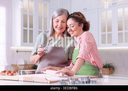 Glückliche Mutter und Tochter kochen zusammen am Tisch in der Küche Stockfoto