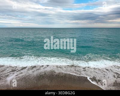 Malerischer Blick auf die Küste mit weißem Meeresschaum, der über dunklem Kiesstrand gespült wird Stockfoto