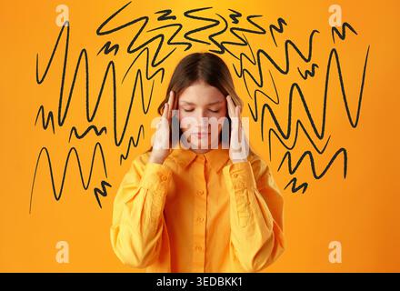 Frau in gelbem Hemd hält ihren Kopf vor einem abstrakten orangen Hintergrund Stockfoto