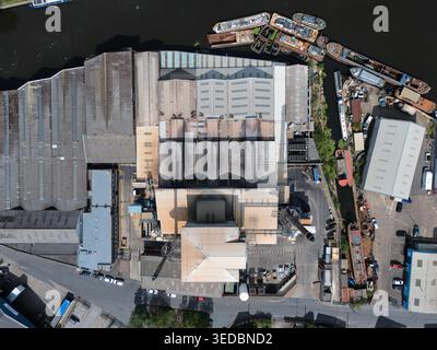 Aus der Vogelperspektive auf die Industriedächer und die großen Fabrikgebäude entlang des Kanals mit verankerten Lastkähnen und Booten in Knottingley, England, United Stockfoto
