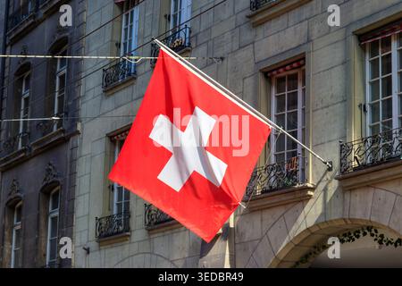 Rote Schweizer Flagge hängt an der Gebäudefassade Stockfoto