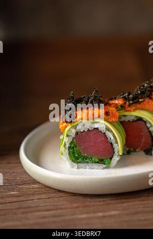Sushi-Brötchen mit Thunfisch-Avocado und scharfem Topping Stockfoto