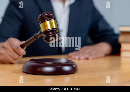 Nahaufnahme eines Richters, der einen Holzhammer auf einen Tonblock schlägt, um ein endgültiges Urteil in einem Gerichtsverfahren zu Fällen. Stockfoto