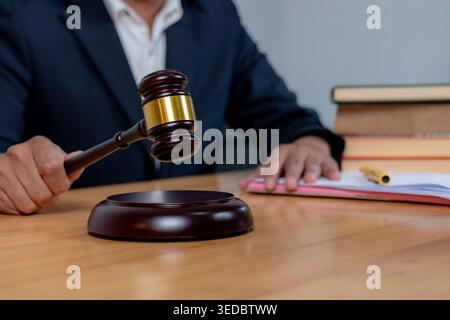 Nahaufnahme eines Richters, der einen Holzhammer auf einen Tonblock schlägt, um ein endgültiges Urteil in einem Gerichtsverfahren zu Fällen. Stockfoto