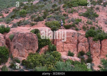 Lone Runner oder Single Male Cross Country Runner oder Jogger, der durch eine dramatische Landschaft oder Landschaft von Sandstone Boulders oder Rocks läuft Stockfoto