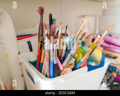 Lebendige Sammlung gebeizter Künstlerpinsel in einem Behälter, die die Schönheit des kreativen Prozesses symbolisieren. Perfekt für Bildungsblogs, Kunstschule A Stockfoto