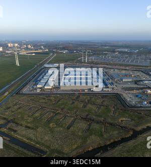Luftaufnahme der KI-Anlage des Rechenzentrums mit Solarpaneelen auf dem Dach, umgeben von Grünflächen und industrieller Infrastruktur in den Niederlanden. Stockfoto