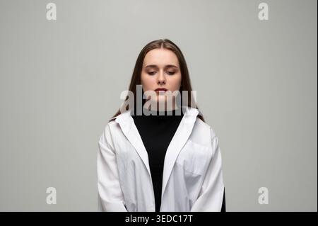 Junge Frau fühlt sich niedergeschlagen, reflektiert Traurigkeit und Verzweiflung, erlebt Depressionen und psychische Probleme, blickt weg von der Kamera Stockfoto