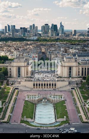 Blick aus der Vogelperspektive auf die Trocadero-Gärten und den Palais de Chaillot mit Menschen, die in der Nähe der Brunnen und der modernen Skyline von La Defense in der Ferne i laufen Stockfoto