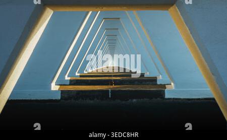 Die geometrische Perspektive erzeugt einen endlosen Lichttunnel, der den Blick auf einen ätherischen Horizont lenkt. Stockfoto