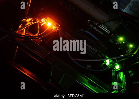Ein optisch beeindruckendes Bild mit dunkler Elektronik, die von leuchtendem Orange und Grün beleuchtet wird. Diese fesselnde Szene hebt die komplizierten d Stockfoto