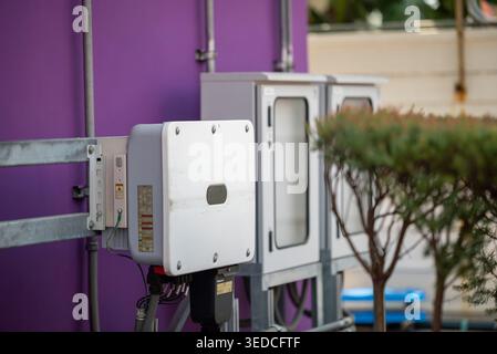 Dieses Bild zeigt eine Elektronikbox an einer violetten Wand, die moderne Technologie und Versorgungsausrüstung in einem urbanen Außenbereich zeigt. Stockfoto