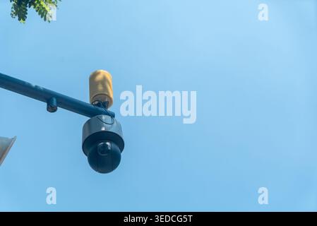 Eine Überwachungskamera, die auf einem blauen Pfosten gegen einen klaren Himmel montiert ist. Das Gerät dient zur Überwachung von Sicherheit und Überwachung in städtischen Umgebungen. Stockfoto