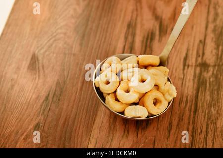 Traditioneller Taralli-Snack in Kelle auf Holztisch, süßer oder herzhafter kleiner ringförmiger Snack Stockfoto