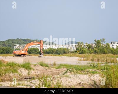 Baustelle für ein großes Immobilienentwicklungsprojekt. Ein Bagger befindet sich auf einem flachen, freigelegten Grundstück. Phu Quoc, Vietnam Stockfoto