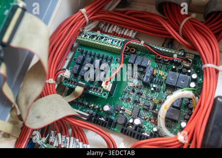 Detaillierte Ansicht einer elektrischen Leiterplatte, umgeben von Verkabelung, mit Komponenten und Verbindungen, die für moderne technologische Systeme und erforderlich sind Stockfoto