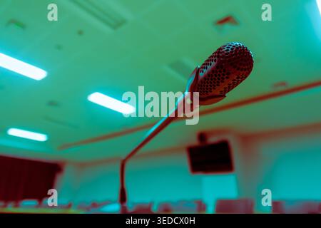 Nahaufnahme eines Mikrofons auf einem Standfuß in einem leeren Konferenzraum, ideal für Themen wie Kommunikation, Präsentationen und professionelle Veranstaltungen. Stockfoto