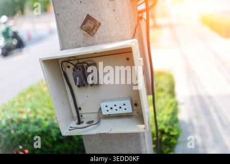 Nahaufnahme eines elektrischen Anschlusskastens, der an einem Versorgungsmast montiert ist, mit Stromanschlüssen und Kabeln. Ideal für die Illustration städtischer Infrast Stockfoto