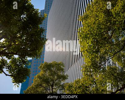 Fassaden moderner Hochhäuser durch die grünen Bäume an einem hellen sonnigen Tag im Bezirk Nagatacho, Chiyoda City, Tokio, Japan. Stockfoto