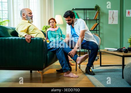 Professioneller indischer junger männlicher orthopädischer Arzt oder Physiotherapeut, der eine Knieverletzung eines älteren männlichen Patienten in einer modernen Klinik überprüft; Healthcare, Mo Stockfoto