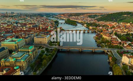 Blick aus der Vogelperspektive auf die Karlsbrücke und die Moldau, umgeben von historischen Gebäuden mit roten Dächern und üppigem Grün während des Sonnenuntergangs in Prag, Prag, Czec Stockfoto
