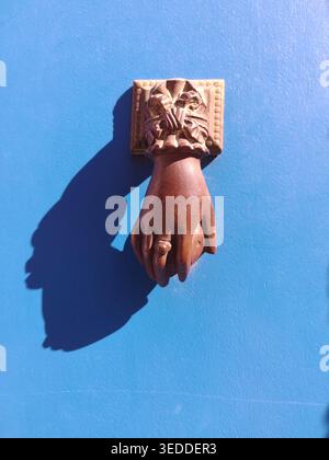 Traditioneller handgeformter Türklopfer an einer rustikalen blauen Holztür Stockfoto