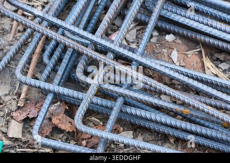 Zuverlässiges, schweres, stabiles Stahlmaterial, Bewehrungsstab aus Metall, gestapelt auf unbefestigtem Boden, das solide industrielle Rohmaterial zeigt Stockfoto