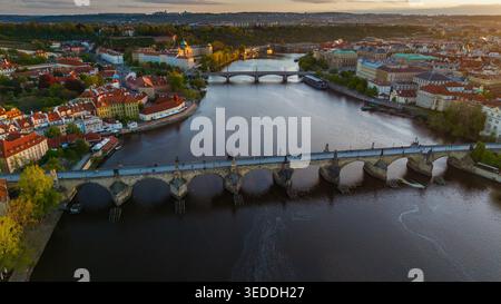 Blick aus der Vogelperspektive auf die historische Karlsbrücke mit Menschen, die während des Sonnenuntergangs in Prag, Prag, Tschechien, über die Moldau laufen. Stockfoto