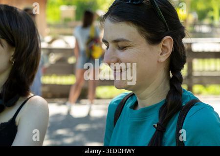 Frau mittleren Alters lächelt mit geschlossenen Augen im Sommerpark. Stockfoto