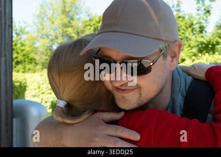 Erwachsener Sohn umarmt seine ältere Mutter draußen im Park. Stockfoto