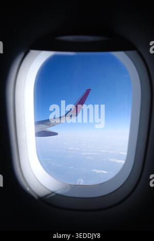 Blick vom Flugzeugfenster mit Flügel über blauem Himmel und Horizont Stockfoto