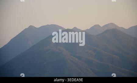 Mehrschichtige Bergsilhouetten in sanftem, trübem Licht bei Sonnenaufgang oder Abenddämmerung, Landschaft von Hongkong Stockfoto