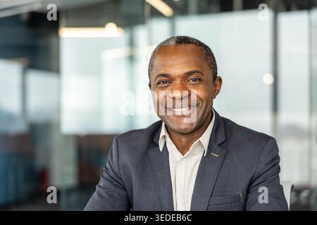 Erfahrener professioneller Mann, der Wärme und Erfolg ausstrahlt, in einem modernen Büroumfeld steht, Führungsstärke und positive Geschäftsinteraktion verkörpert Stockfoto