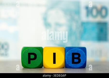 PIB-Akronym auf Holzblöcken in brasilianischen Farben mit echter 100-Banknote. Konzept des Bruttoinlandsprodukts für die brasilianische Wirtschaft Stockfoto