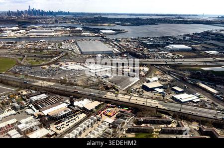 Aus der Vogelperspektive auf den Industriebereich mit Lagerhäusern, belebten Highways und der entfernten Skyline von New York City in Elizabeth, New Jersey, U Stockfoto