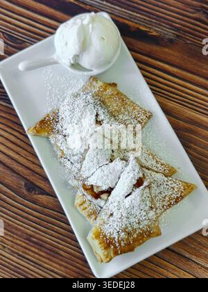 Strudel aus Hefefreiem Blätterteig mit Äpfeln, mit Puderzucker und einer Eiskugel bestreut. Süßes Dessert für Kaffee oder Tee. T Stockfoto