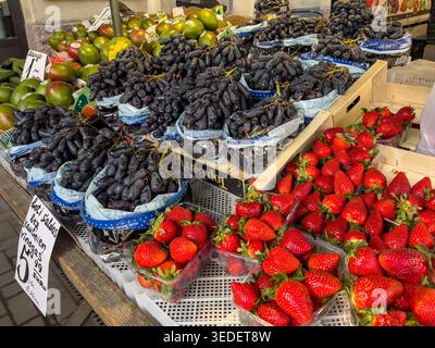 Exotische Obstauswahl auf dem lokalen Markt - Trauben, Erdbeeren und tropische Mango auf dem zentralen Markt, mit saisonaler Vielfalt Stockfoto